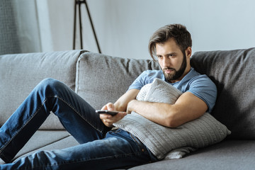 Sad lonely man holding a remote control