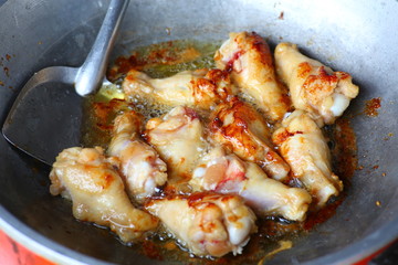 Chicken legs frying in a pan.