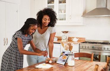 Teenage Girls Following Recipe On Digital Tablet