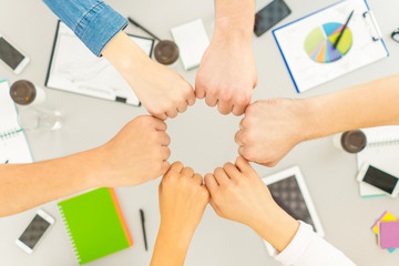 The six people hold fists at the desktop. view from above