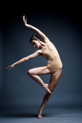Fototapeta premium A beautiful athletic girl in a black dress is dancing. In move