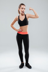 Fototapeta na wymiar Full length portrait of a young sportswoman flexing muscles