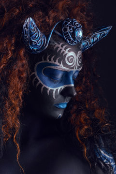 Fabulous female from fairytale with blue black body art, corset and horns