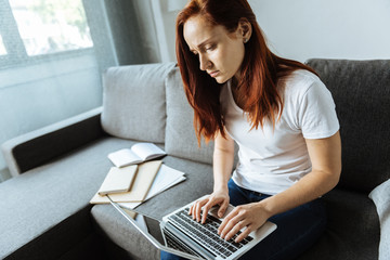 Cheerless smart woman typing on the keyboard