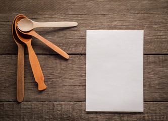 different wooden spoons on the rustic background with blank notepad.