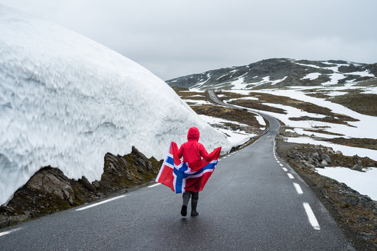 Girl with a Norwegian flag on a mountain road in Norway