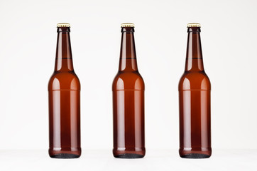 Three brown longneck beer bottles mock up. Template on white wood table.