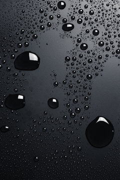 Black water drops on dark surface