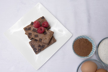 Chocolate brownie slices with raspberries, coco powder and eggs. 