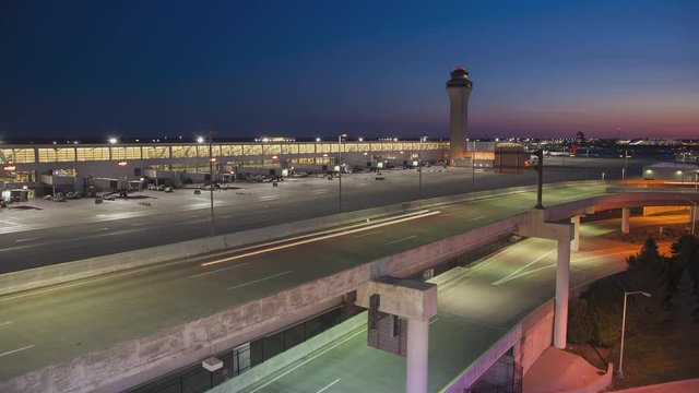 Detroit MI DTW Airport Early Morning Timelapse with Arriving Vehicle Traffic with Light Streaks from Driving Cars and the Air Control Tower in a Vibrant Colorful Sky Background