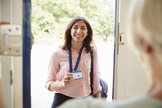 Female care worker on home visit showing her ID, close up