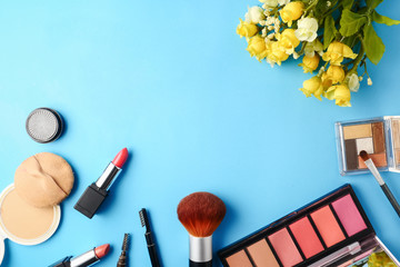 Top view of cosmetics set for makeup on a blue background. Free space for text.