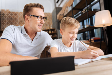 Upbeat boy doing math home assignment with father