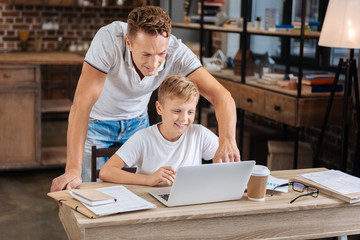 Caring father helping his son with laptop settings