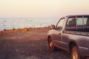 Pickup car parked on shore. Gentle pink sunset. © redche