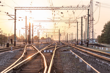 Fototapeta na wymiar An empty railway sorting station or terminal with lots of junction, crossroads, semaphore showing red or green light, in a bright sunset light.