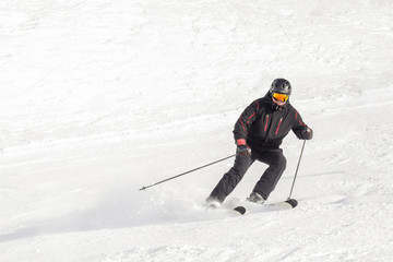 Fototapeta na wymiar Adult confident male skier in a black ski suite stand on a downhill
