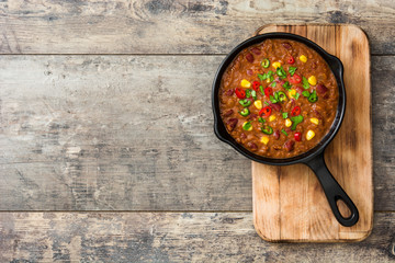 Traditional mexican tex mex chili con carne in a frying pan on wooden table.Top view
