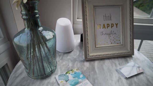 Think happy thoughts printed inside a picture from on an end table with flowers.