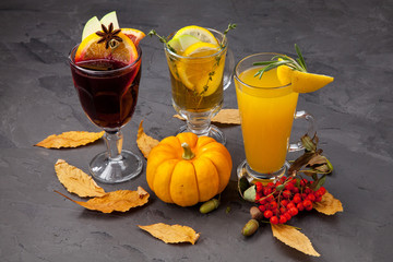 a still-life of alcoholic autumn warming drinks, cocktails, mulled wine with pumpkins, yellow leaves and rowan