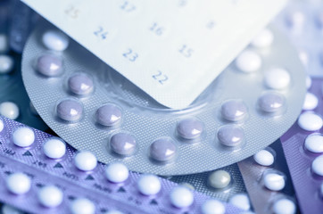 Oral contraceptive pill on pharmacy counter with colorful pills strips background.
