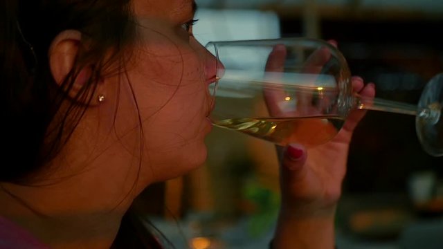 Girl sitting in a cafe drinking white wine from a glass, close-up. HD, 1920x1080. slow motion.
