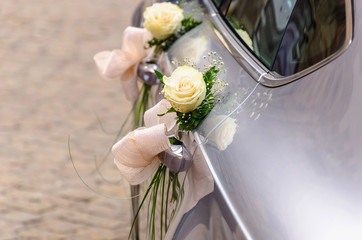 Obraz premium Wedding car decorated with white roses ready to carry just married direct to honeymoon
