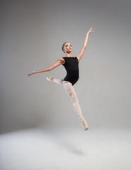 Obraz premium Elegant ballerina in black tights floating in the air