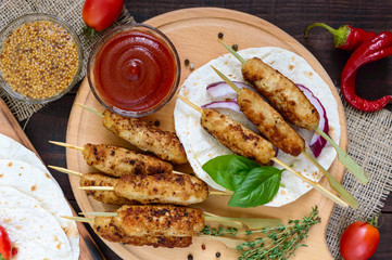 Traditional Caucasian dish is lula kebab. Serve with lavash, tomato sauce, mustard on a dark wooden background. Top view.