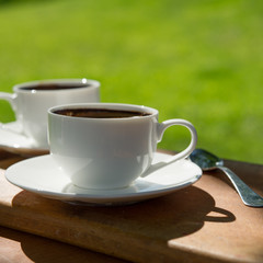 two cups with hot coffee on a wooden board in a cafe