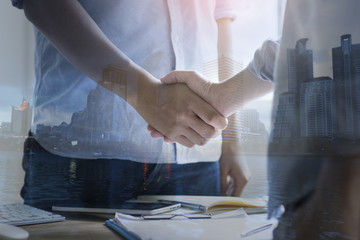 Obraz na płótnie Canvas double exposure businessman shaking hand and city, concept as team work and cooperation in success business
