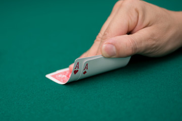 Poker player lifting the corners of two cards