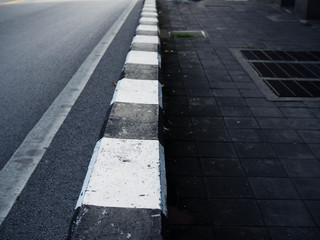 Black and white paved road border, with dark stone cement tile footpath floor and water drainage sewage iron mesh cover, depth extending, perspective