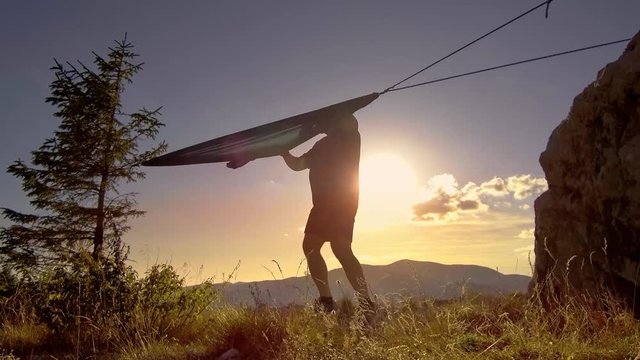 man relaxing in hammock at sunset in the mountains
