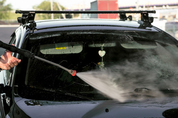 Car washing. Car cleaning using high pressure water. Worker washes the car.