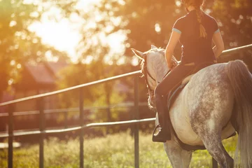 Rolgordijnen Woman riding a horse on paddock, horsewoman sport wear © leszekglasner