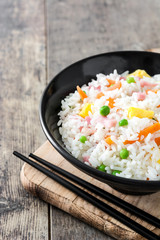 Chinese fried rice with vegetables and omelette on wooden table
