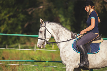 Woman riding a horse on paddock, horsewoman sport wear