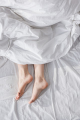 Fototapeta na wymiar female feet stretching out of blanket