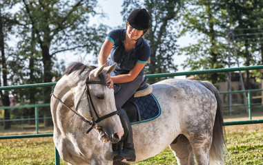 Woman riding a horse on paddock, horsewoman sport wear
