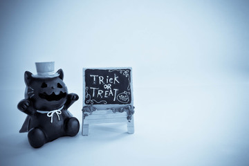 Black cat raisin and a little blackboard "trick or treat", halloween props in halloween tones.