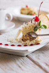 Tasting of creamy orange dessert serving in restaurant. Delicious cake with decoration from cherry, white chocolate and mint, close up picture