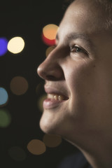 Teenage Boy in front of Christmas Lights, taken in a dark room with Colorful Bokeh in the Background