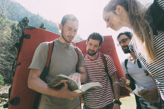 Adult bouldering friends looking at guide book, Lombardy, Italy