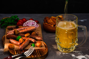 Grilled sausages with glass of beer on black table. Oktoberfest.