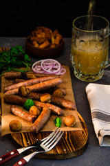 Grilled sausages with glass of beer on black table. Oktoberfest.