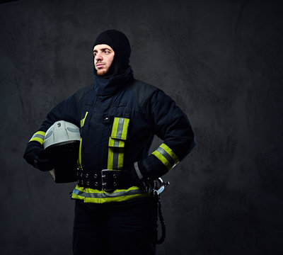 Firefighter in a uniform holds safety helmet.