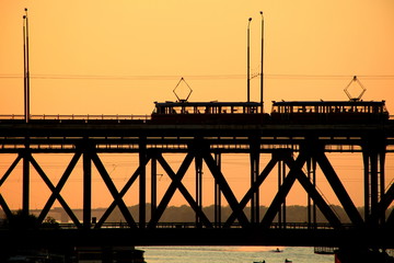 Silhouettes of a two-tiered bridge and 2 trams on a sunset ,  Dnepr city, (Dnepropetrovsk, Dnipropetrovsk,  Dnipro) , Ukraine
