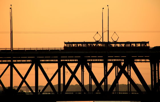 Fototapeta Silhouettes of a two-tiered bridge and 2 trams on a sunset background ,  Dnepr city, (Dnepropetrovsk, Dnipropetrovsk,  Dnipro) , Ukraine