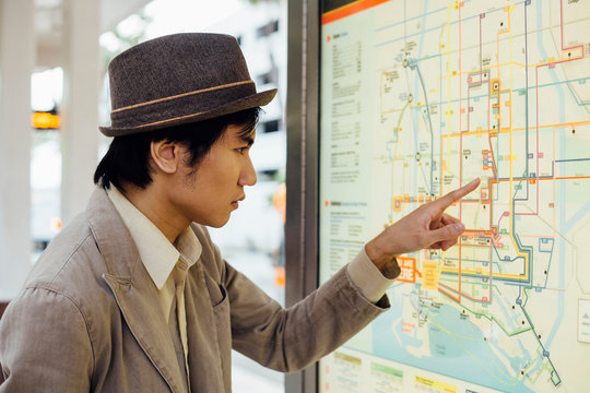 Young man looking at train map at train station